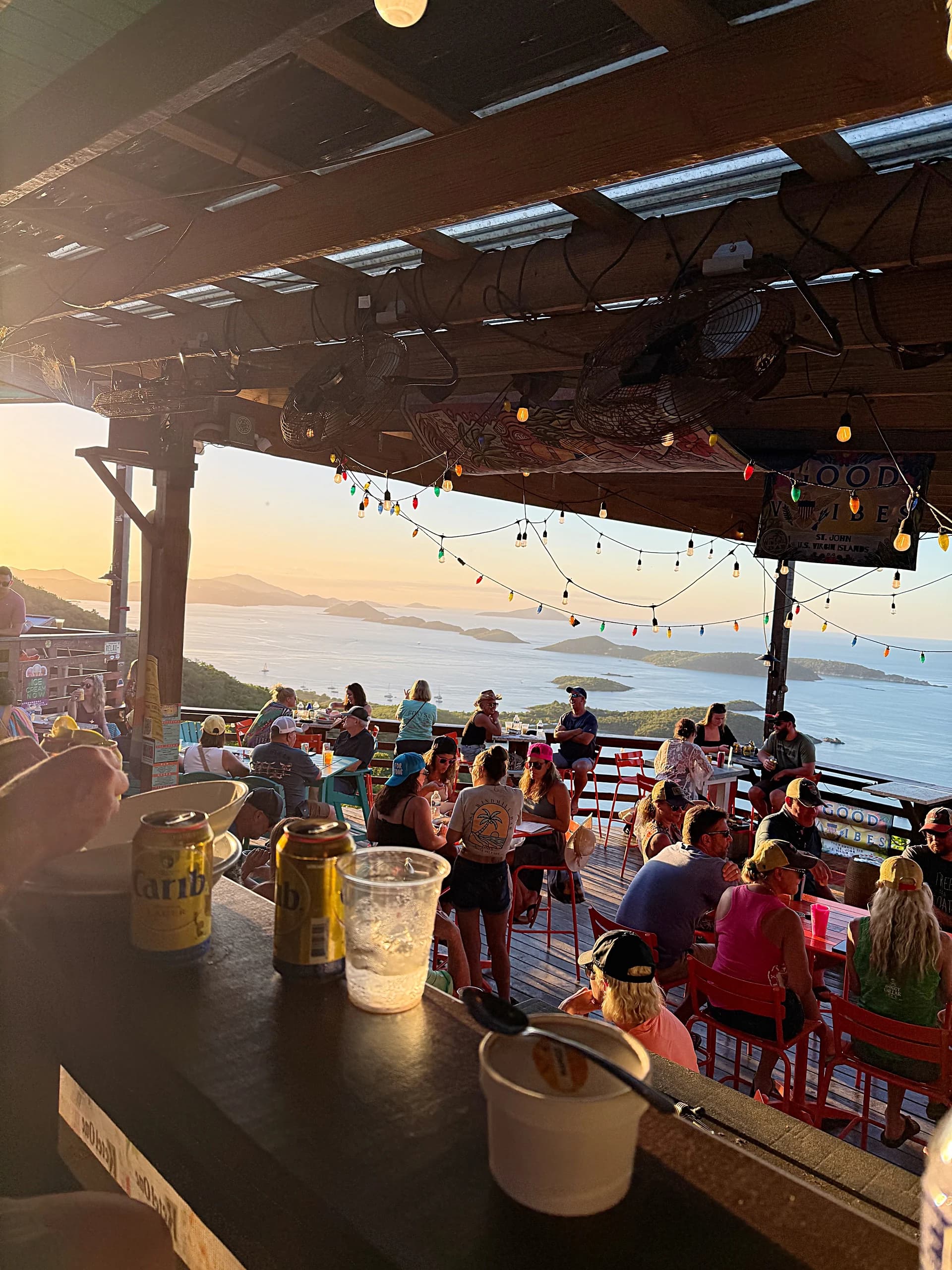 A hilltop bar strung with coloured lights at golden hour, looking out over the islands of the U.S. Virgin Islands.